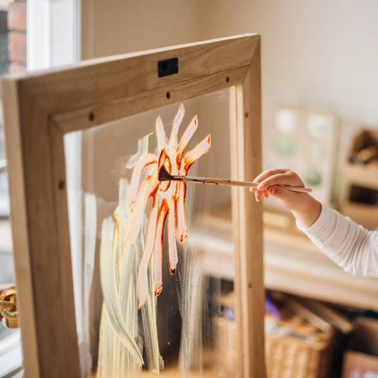 Child painting a picture on a QToys Toddler Perspex Easel with a wooden frame.