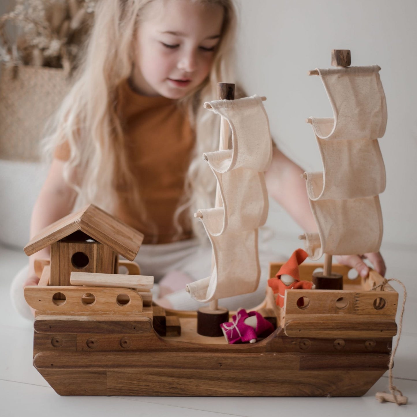 Child playing with a QToys wooden toy pirate ship