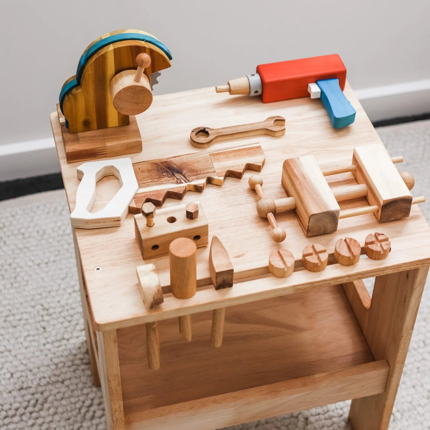 Wooden toy workbench with various tools on a gray background