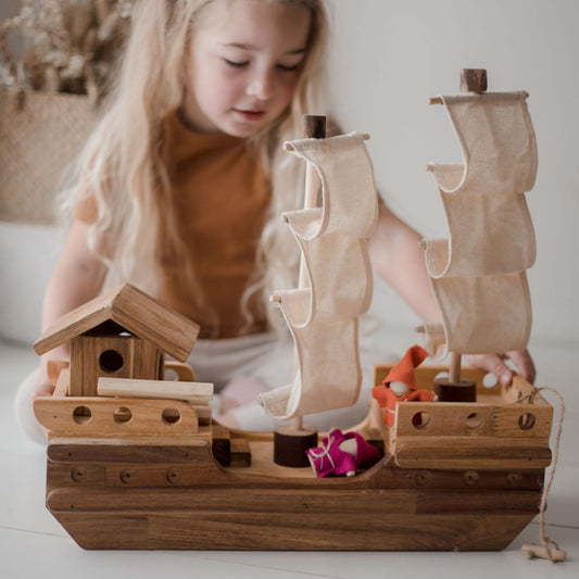 Child playing with a QToys wooden toy pirate ship