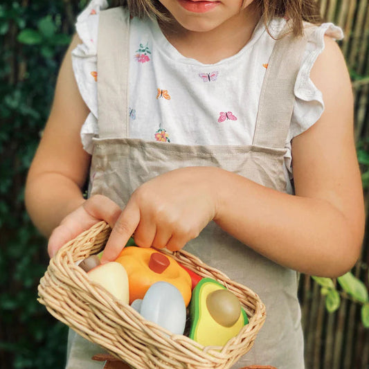 Child holding a Tender Leaf Toys Veggie Basket with toy vegetables.