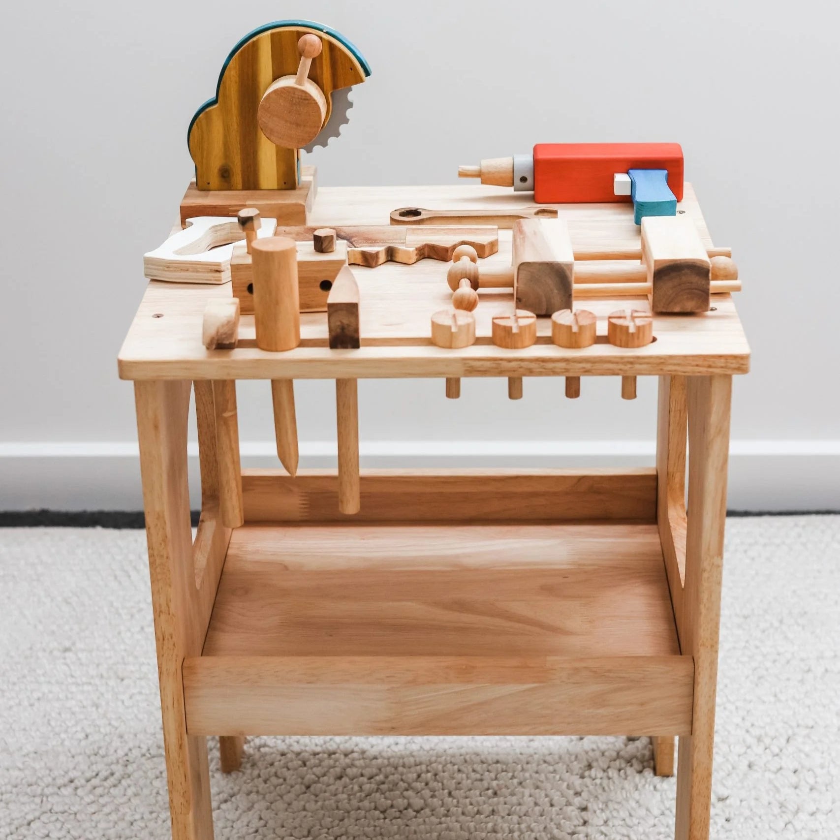 Wooden toy construction set on a light wooden stand against a white wall.